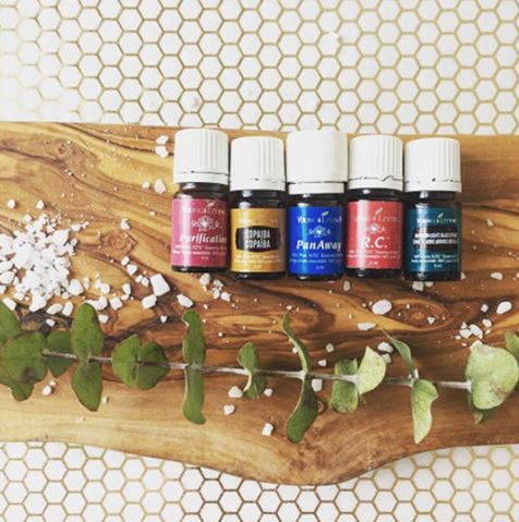 wooden board with 5 essential oils bottles and dried greens